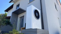 Eine moderne Wärmepumpe steht vor einem Einfamilienhaus.